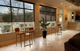 A room with a table and chairs by a window.