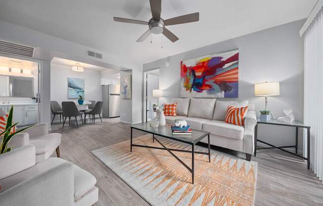 A living room with a white couch, a coffee table, and a ceiling fan.
