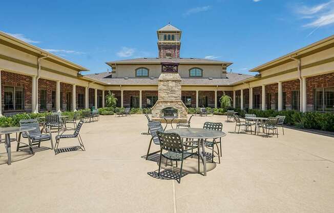 A courtyard with tables and chairs and a building in the background.