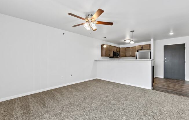 a bedroom with a ceiling fan and a kitchen in the background