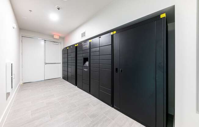 a row of black lockers in a room with white walls and a tile floor