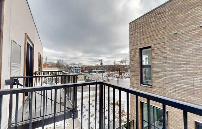 A balcony with a black railing and a view of a snowy landscape at One West Drive Apartments, Excelsior, 55331