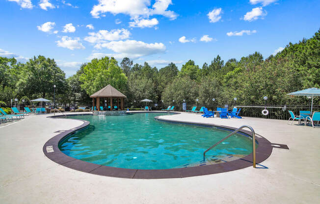 a resort style pool with chaise lounge chairs and a gazebo