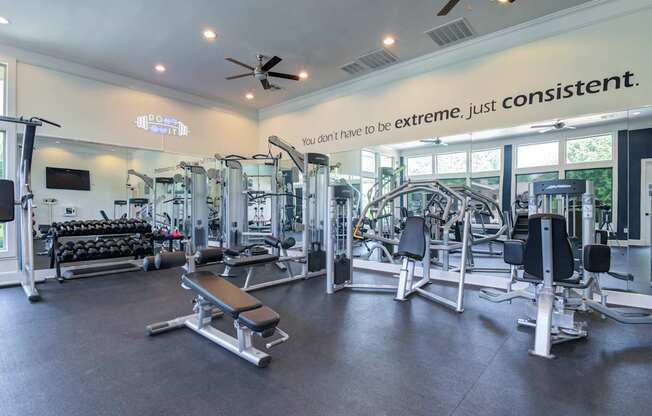 A gym with a variety of equipment and a sign that says "you don't have to be extreme, just consistent.".