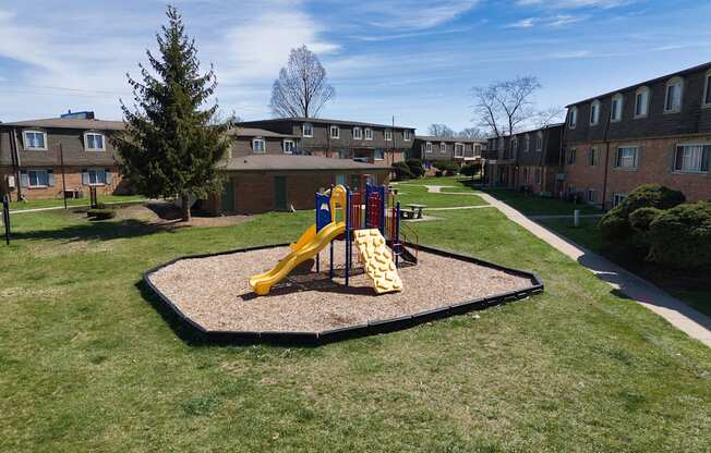 a playground in a yard in front of an apartment building