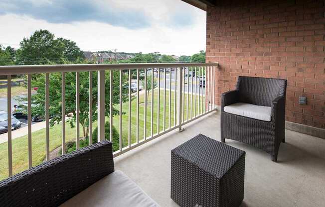 A balcony with a chair and a wicker ottoman.