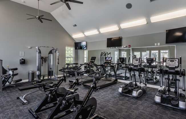 a gym with cardio machines and other exercise equipment and a flat screen tv