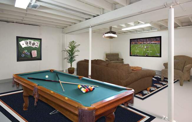 A pool table in a room with a TV showing a football game.