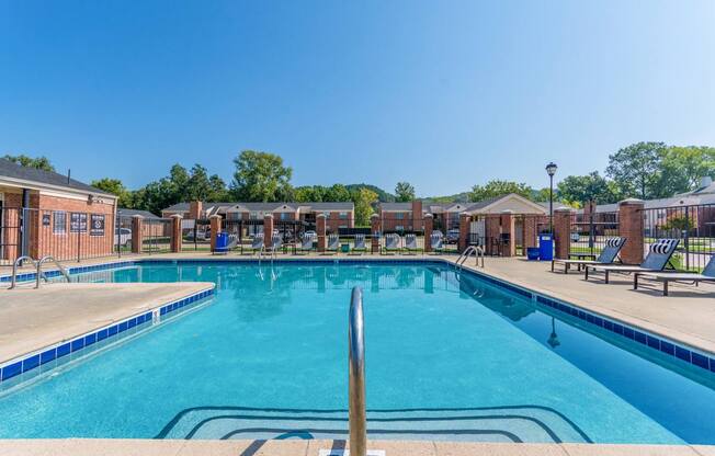 A large swimming pool with a ladder in the middle and sun loungers on the side.