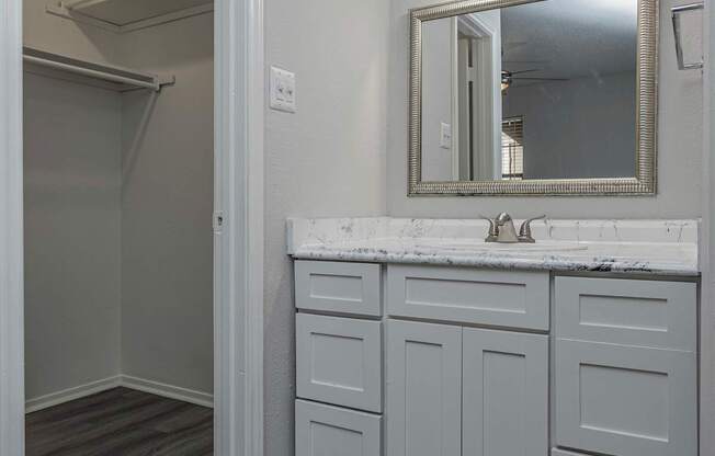 a bathroom with white cabinets and a sink and a mirror