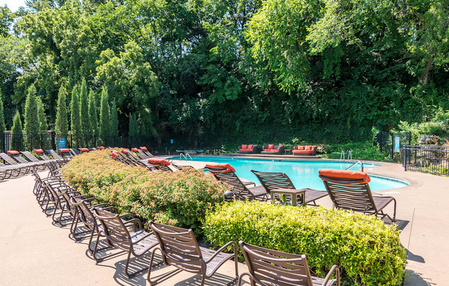 A pool surrounded by trees and chairs.