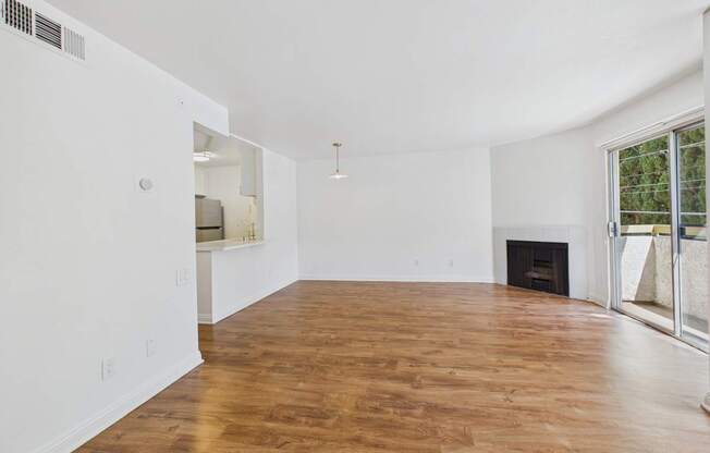A large empty room with wooden floors and white walls.