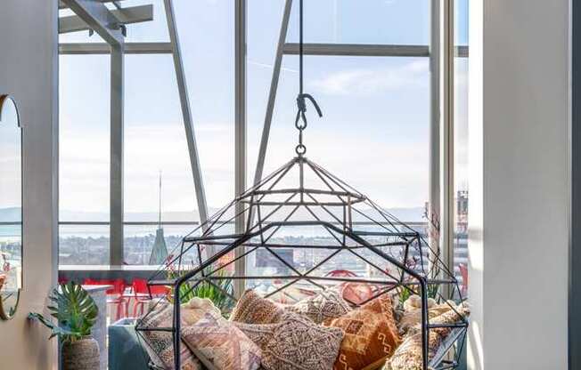 A hanging chair is suspended from a metal frame in a room with a view of the ocean.