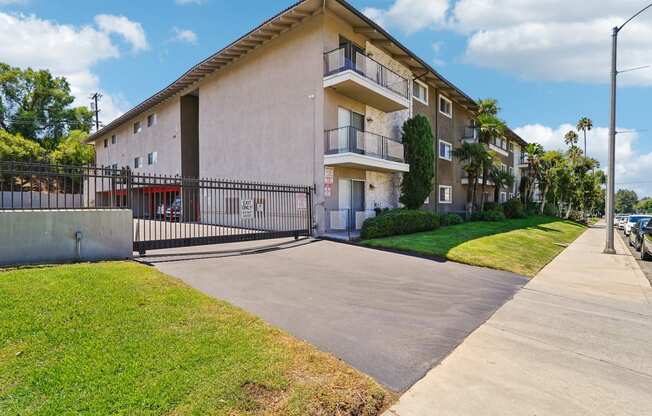 a white apartment building with a sidewalk and grass