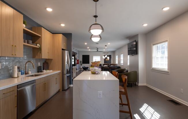 a kitchen with a large island and a living room with a table and chairs