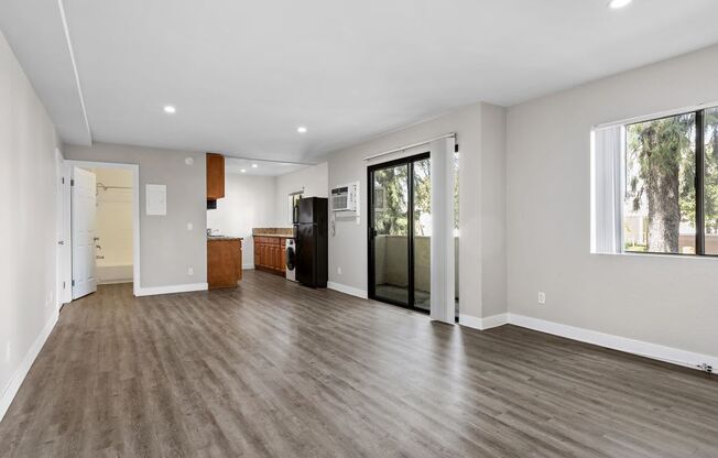 a living room with a hardwood floor and a door that leads to a kitchen