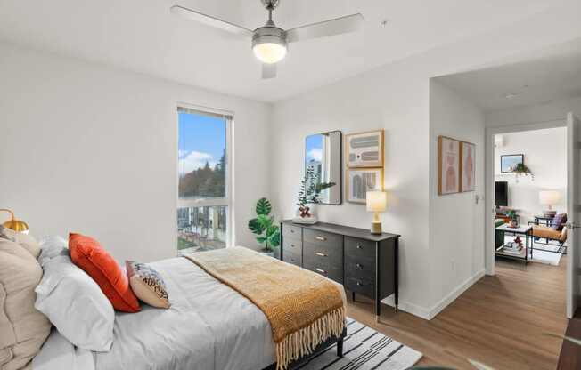 A bedroom with a bed, a dresser, and a ceiling fan.