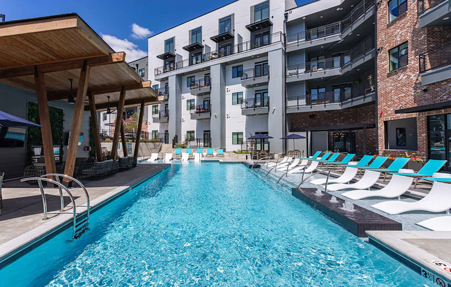 a swimming pool with lounge chairs next to an apartment building