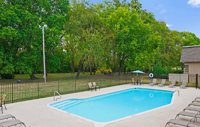 a swimming pool with chairs and a fence around it