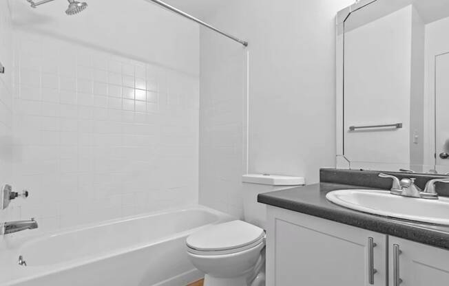 A white bathroom with a toilet, sink, and bathtub.