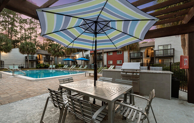 Outdoor BBQ Area with Furniture and Pool View at Heron Walk Apartments in Jacksonville, FL.