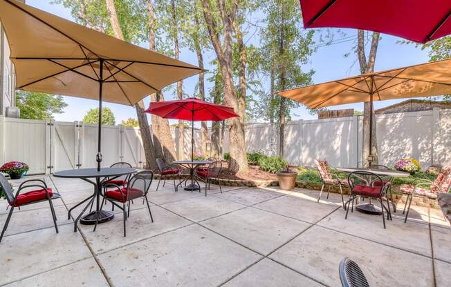 a patio with tables and umbrellas at the whispering winds apartments in pearland, tx