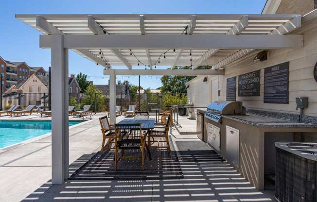 a patio with a grill and a table with chairs and a pool