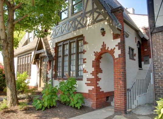 the front of a brick house with a door and a tree