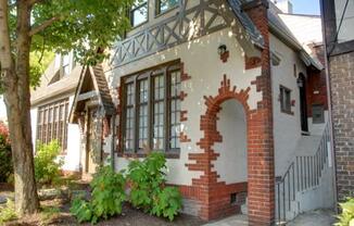 the front of a brick house with a door and a tree