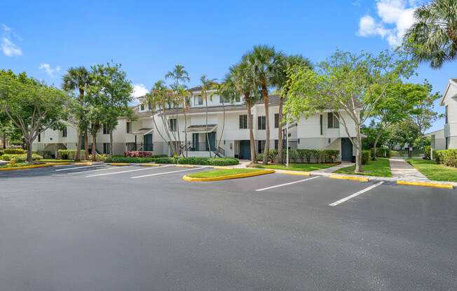 an empty parking lot in front of a building with palm trees