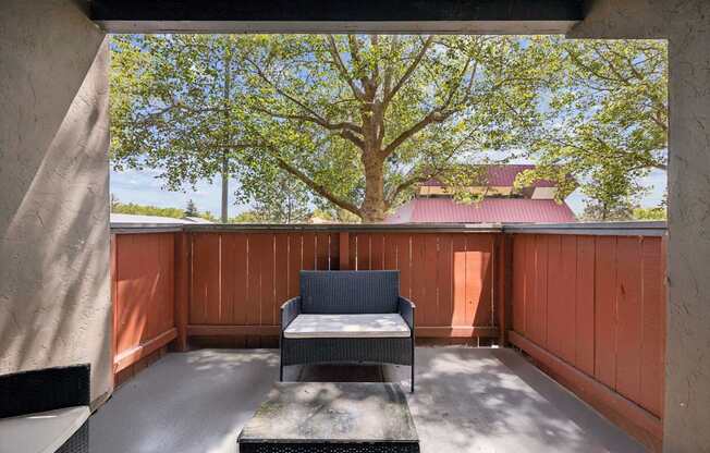 A balcony with a bench and a table with a view of a tree.