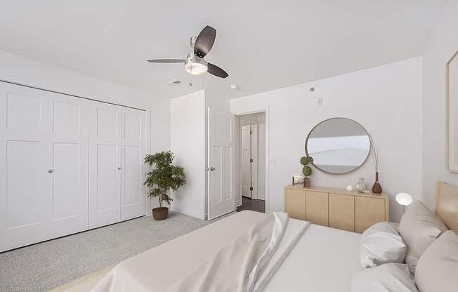 A bedroom with a bed, dresser, mirror, and a ceiling fan at Trade Winds Apartment Homes, Elkhorn, Nebraska