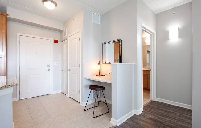 A room with a white door, a table with a black frame and a brown stool.