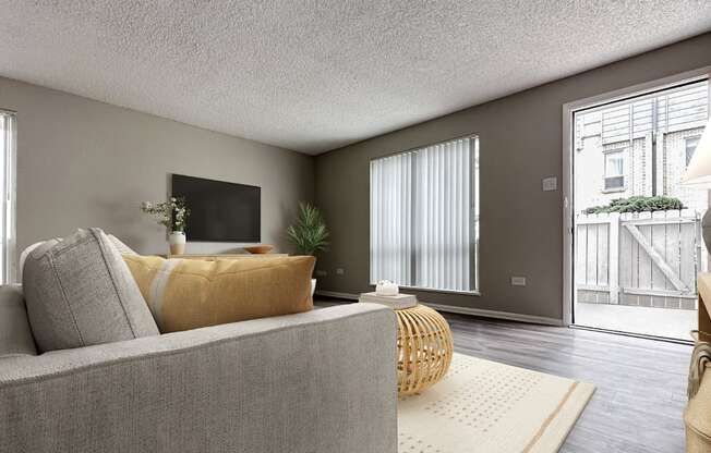 A living room with a grey couch and a yellow pillow.