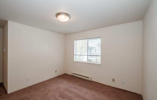 a bedroom with a large window and a carpeted floor