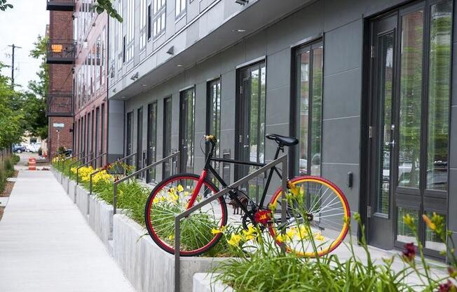 A red bicycle is locked to a post on a sidewalk.