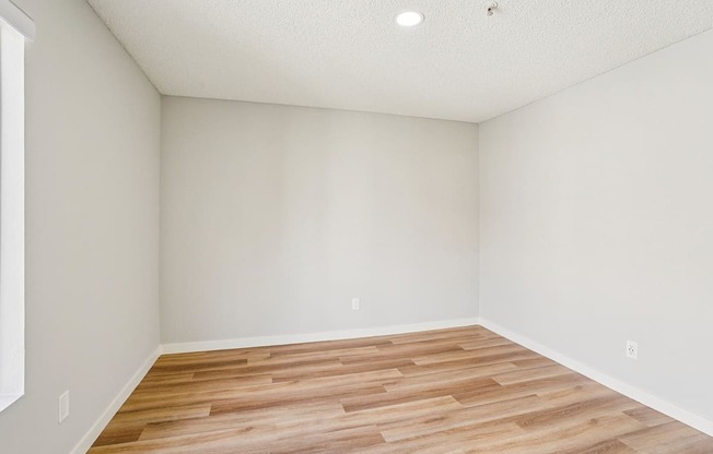 A room with wooden flooring and white walls.