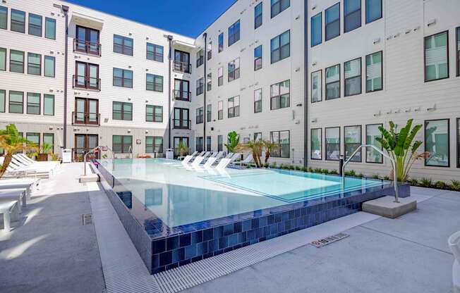 A swimming pool in front of a white building with a blue sky in the background.