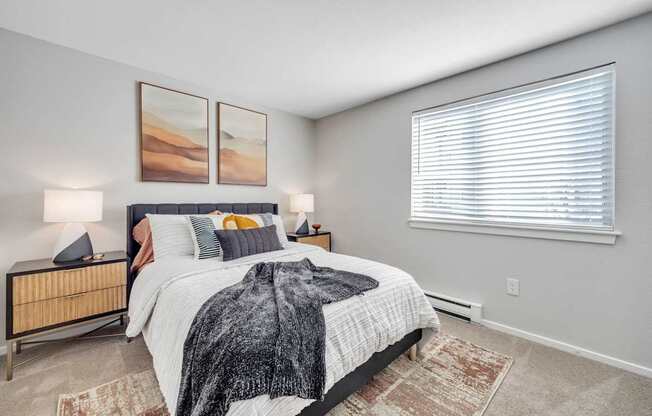 A bedroom with a large bed and two lamps.