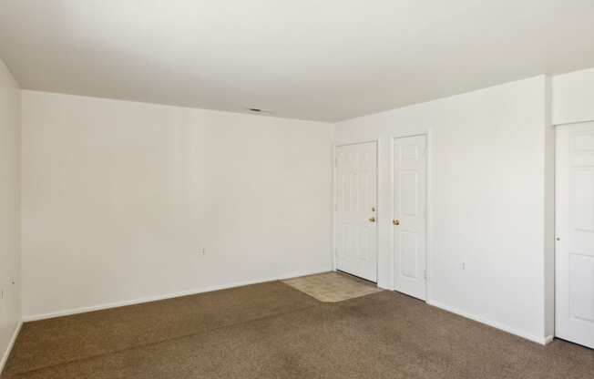 a bedroom with white walls and carpet and two doors