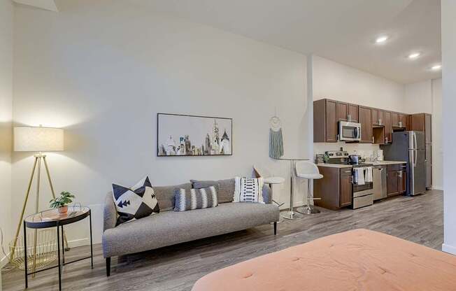 A living room with a grey sofa and a painting on the wall.