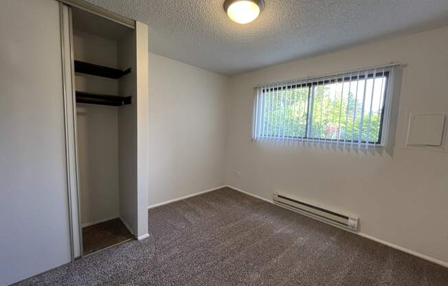 an empty bedroom with a closet and a large window