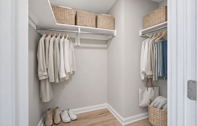 A hallway with clothes hanging and shoes on the floor.