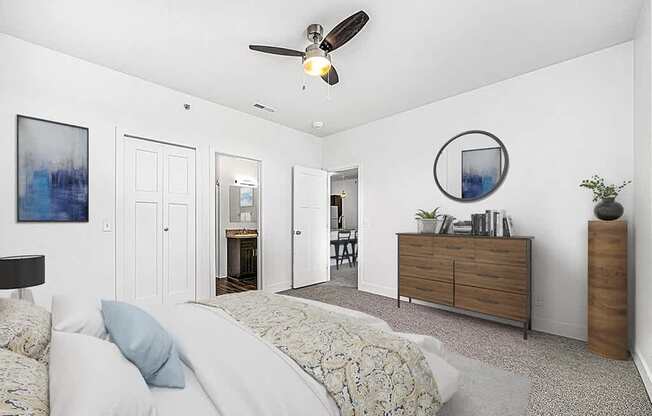 A bedroom with an ensuite, a bed, dresser, and ceiling fan at Trade Winds Apartment Homes, Elkhorn, Nebraska