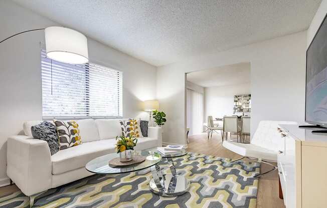 A living room with a white couch and a glass coffee table.