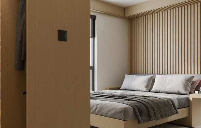 A bedroom with a bed, a nightstand, and a large window with a view of the city.