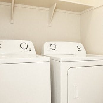 two washer and dryers in a white laundry room