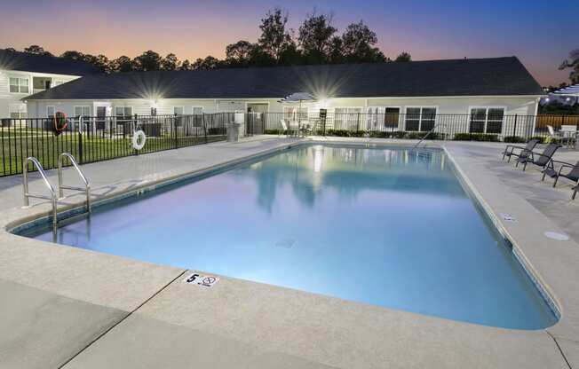 a swimming pool with chairs and a building in the background