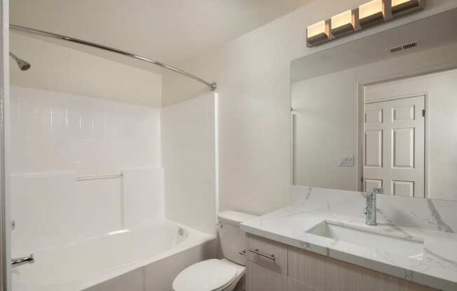 a white bathroom with a tub and a sink and a toilet