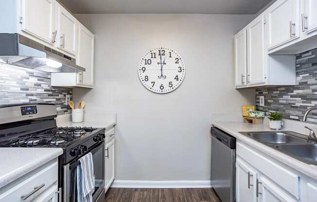 an open kitchen with stainless steel appliances and a large clock on the wall